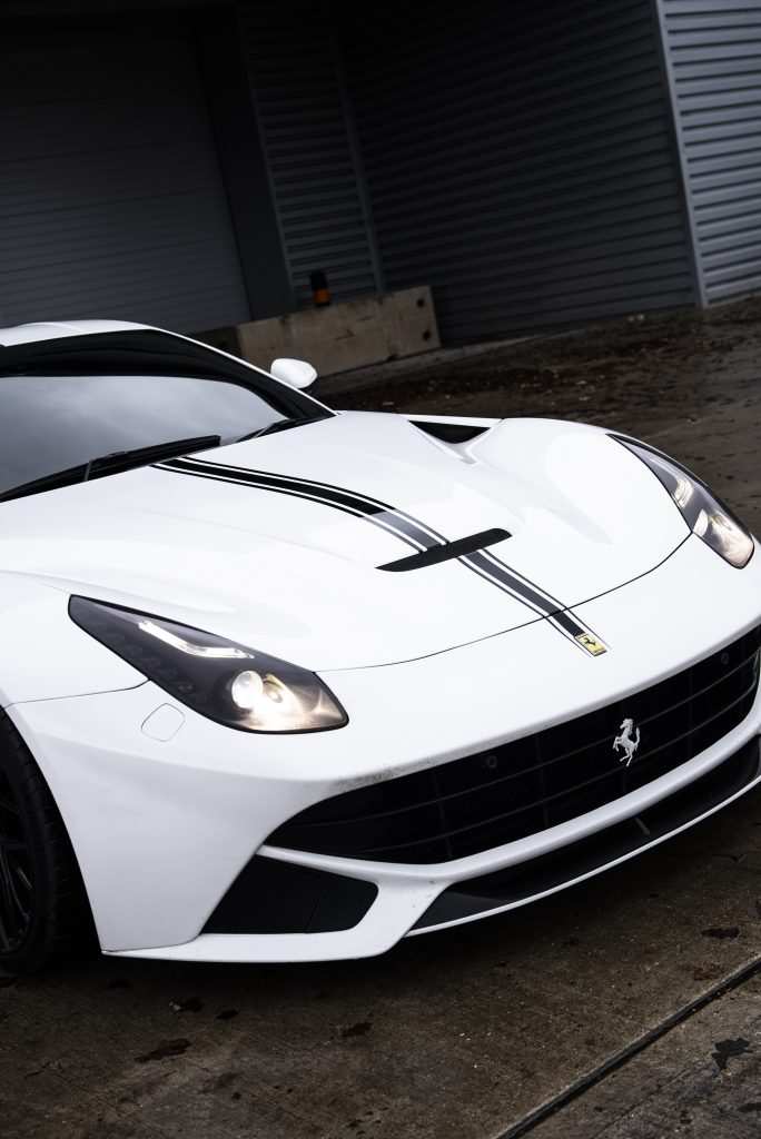 White Ferrari F12 front view with headlights on